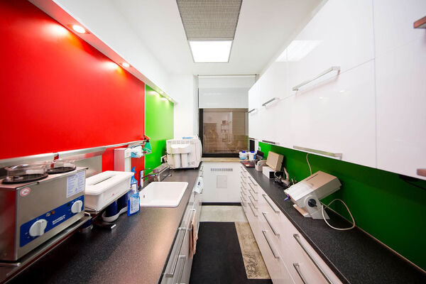 Moderne Zahnarztpraxis Sterilisationsraum mit roten und grünen Wänden und Laborgeräten.