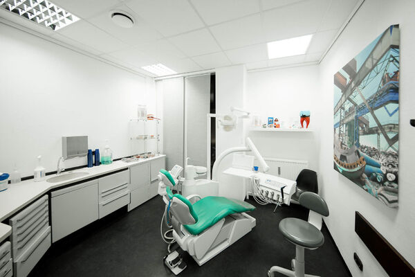 Moderner Zahnarztpraxis-Behandlungsraum mit Behandlungsstuhl, Geräten und heller Einrichtung.