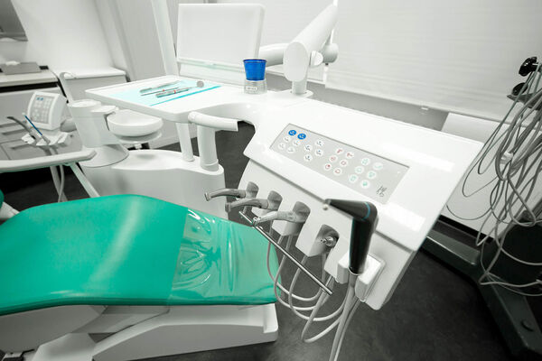 Moderne Zahnarztpraxis mit Behandlungsstuhl, Dentalinstrumenten und Bedienfeld.