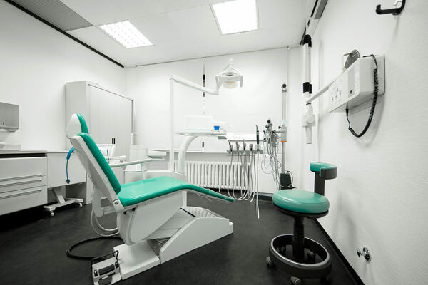 Moderner Behandlungsraum in einer Zahnarztpraxis mit Zahnarztstuhl und Geräten.