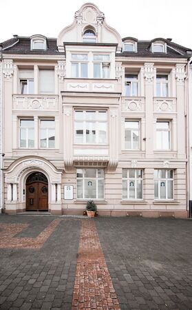 Historische Altbaufassade mit verzierten Fenstern und Eingangsbereich in urbaner Umgebung.